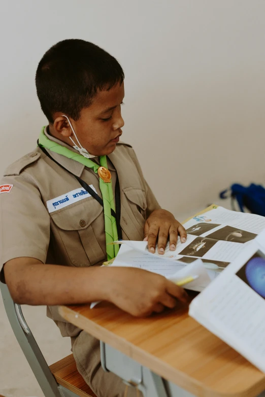 boy wearing scout uniform reading a book