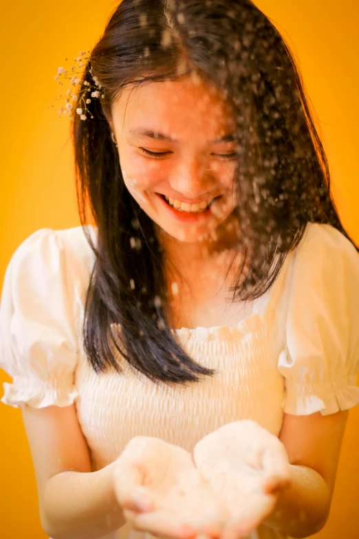 a young asian girl holds soing that she has thrown on her face