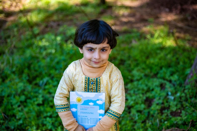 a small boy holds a book in his hand