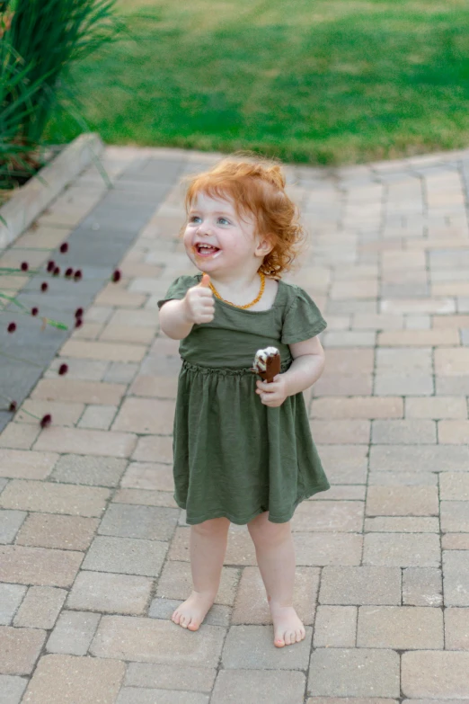  in green dress holding soing to her mouth