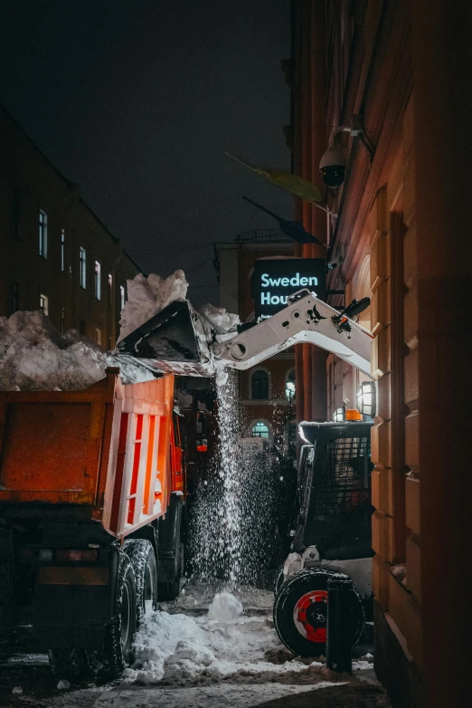 some dump trucks on snowy street next to buildings