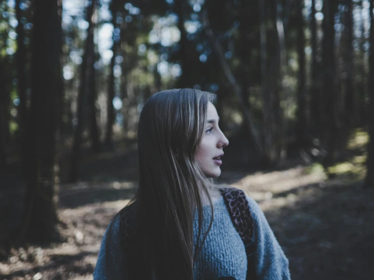 a woman standing in the woods looking up