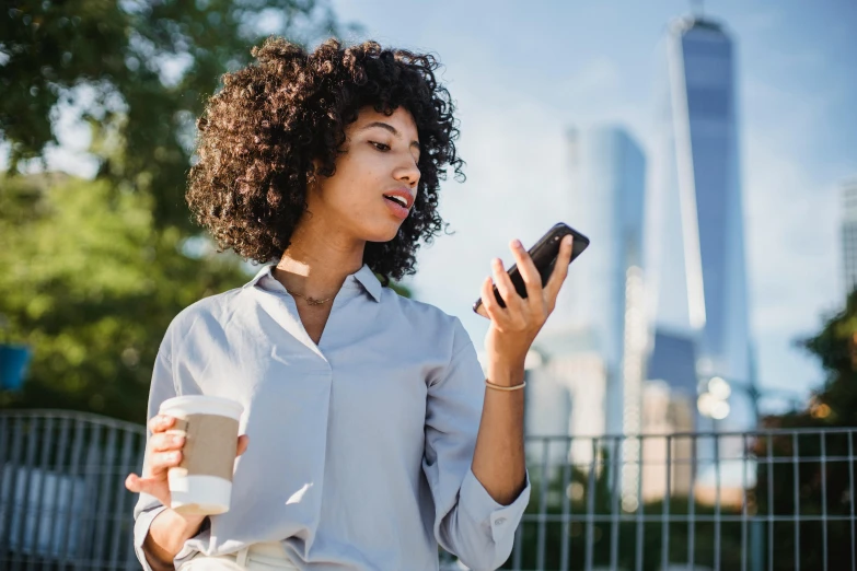 a woman looking at her phone while holding a coffee cup