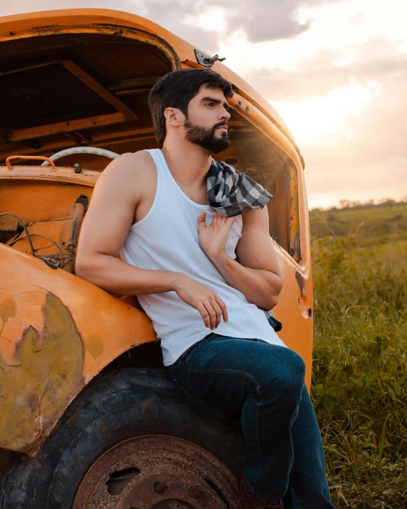 a young man with a scarf sitting on the front of an old yellow truck