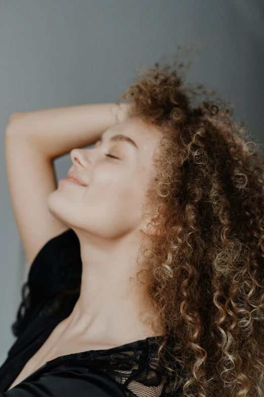 a woman with long curly hair is posed