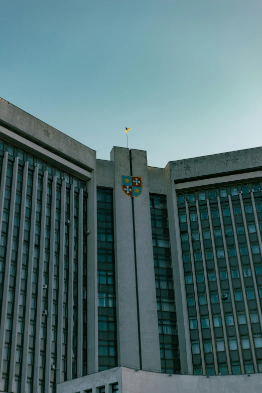 a tall grey building with several flags in front