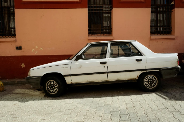 an old white car is parked by a building