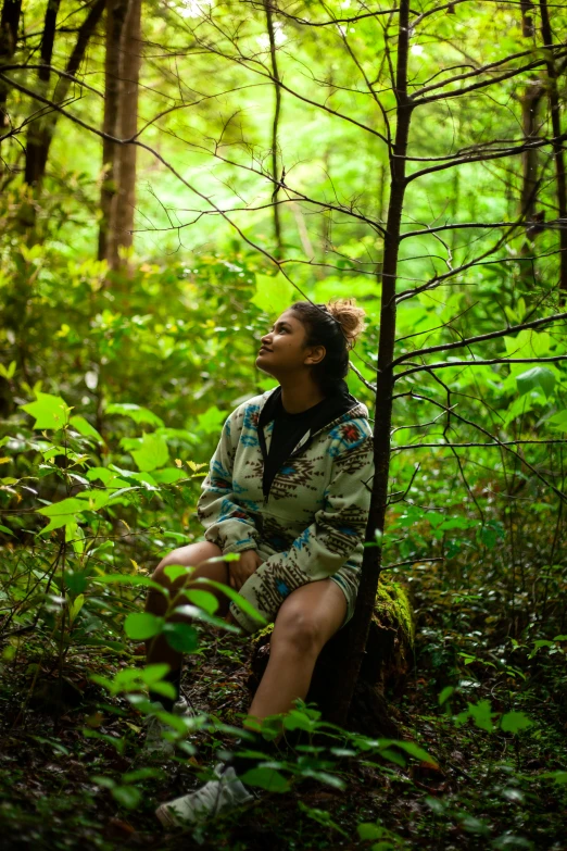 a woman sitting in the middle of a forest