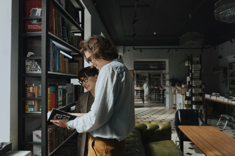 some people standing at a window in front of a book shelf