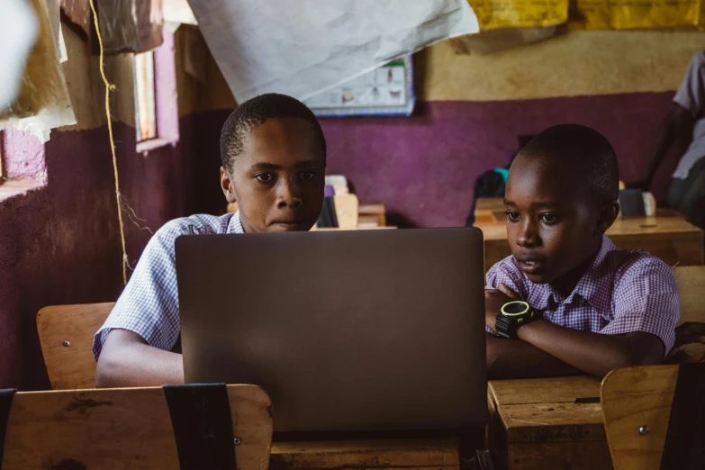 two children using a laptop at desk in front of each other