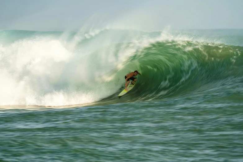 a surfer riding the top of a large green wave