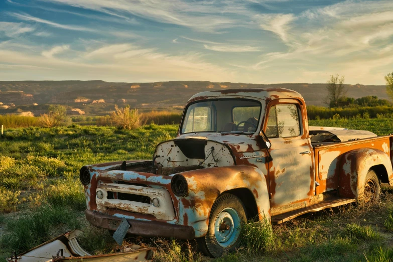 an old rusty, run down pickup truck is in a field