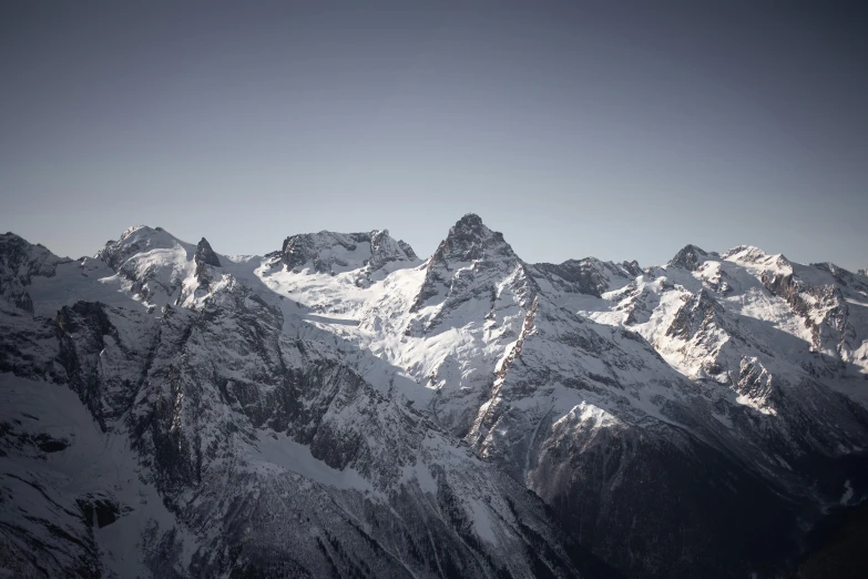 a snow covered mountain range with two skiers on top