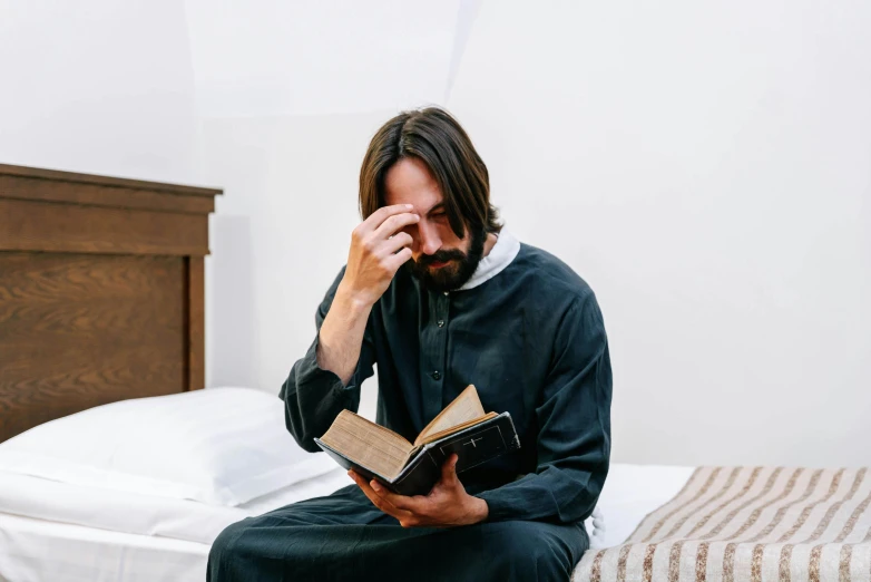 a man is reading the bible on his bed