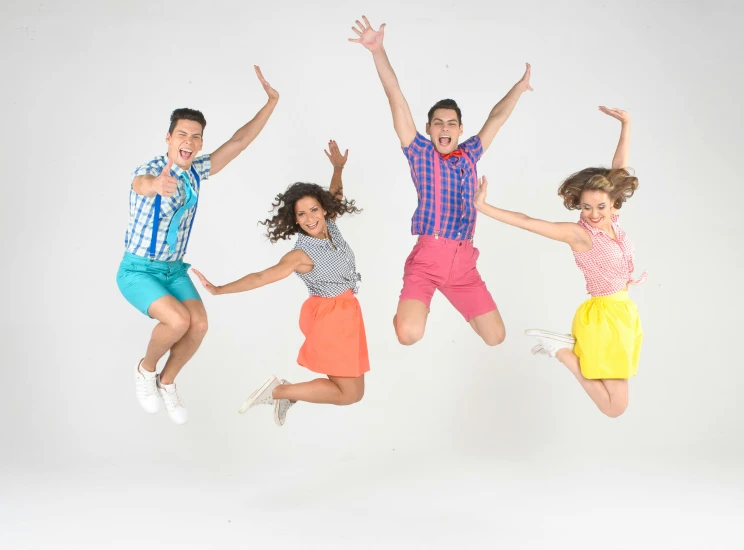 three guys and two girls are jumping for the camera