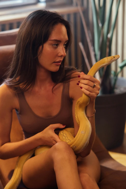 woman holding a yellow snake in her right hand