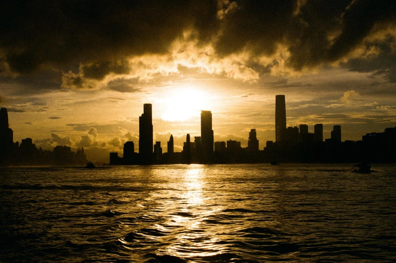 a sunset over a body of water with large city buildings in the background