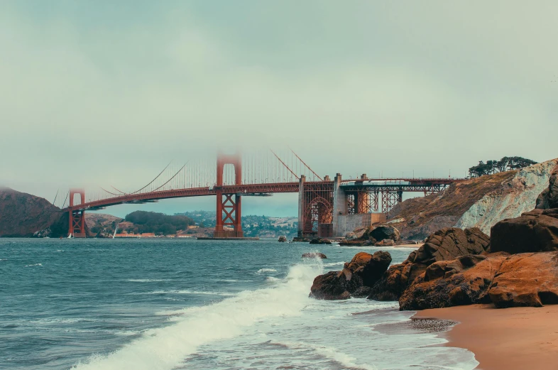 waves and waves wash on the shore with a view of the bridge