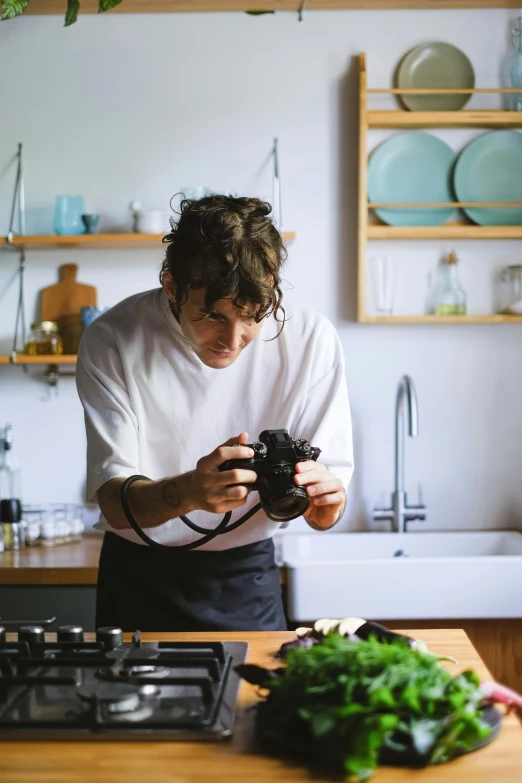 a man holding a camera standing in a kitchen