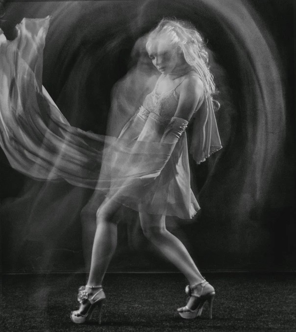 a woman is dancing on the ground with a light painting behind her