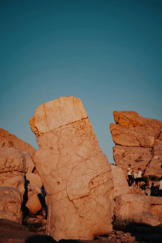 people are standing near huge boulders in the desert