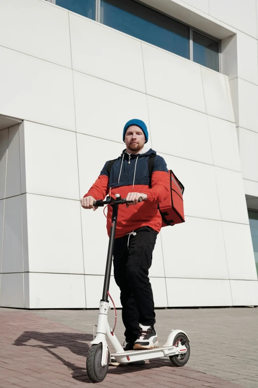 man riding on scooter wearing a bright orange jacket