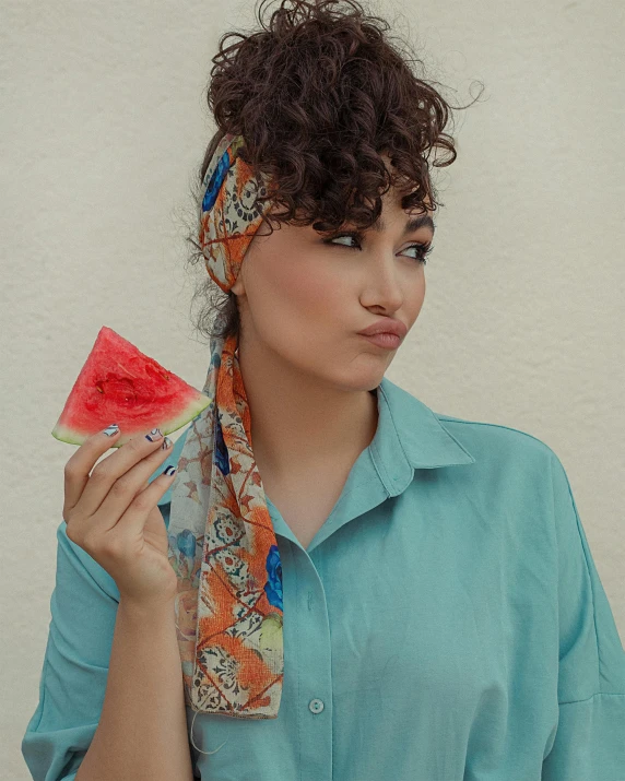 a person holding a piece of watermelon with the other part of their face in their hand