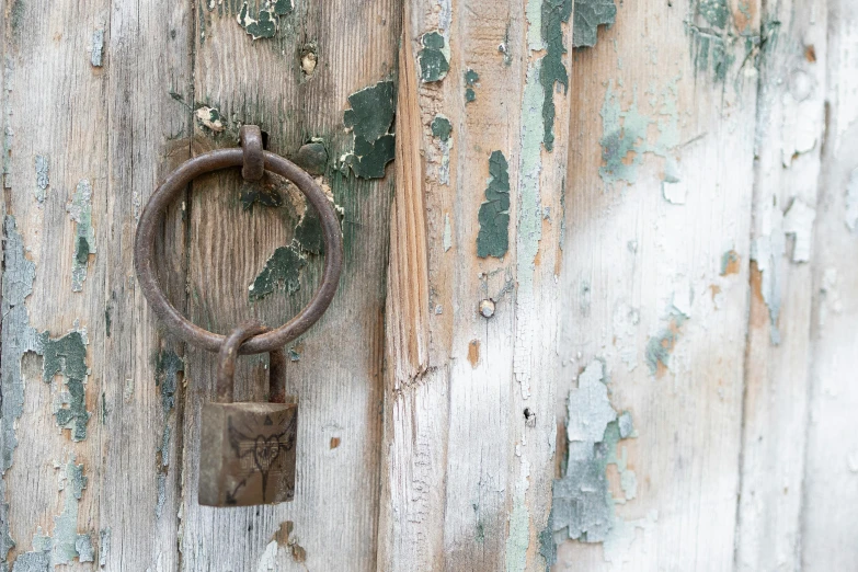 the wall is covered in peeling paint with a padlock attached to it