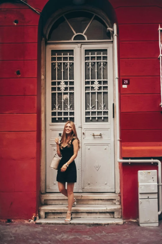 a young woman stands outside an old style door