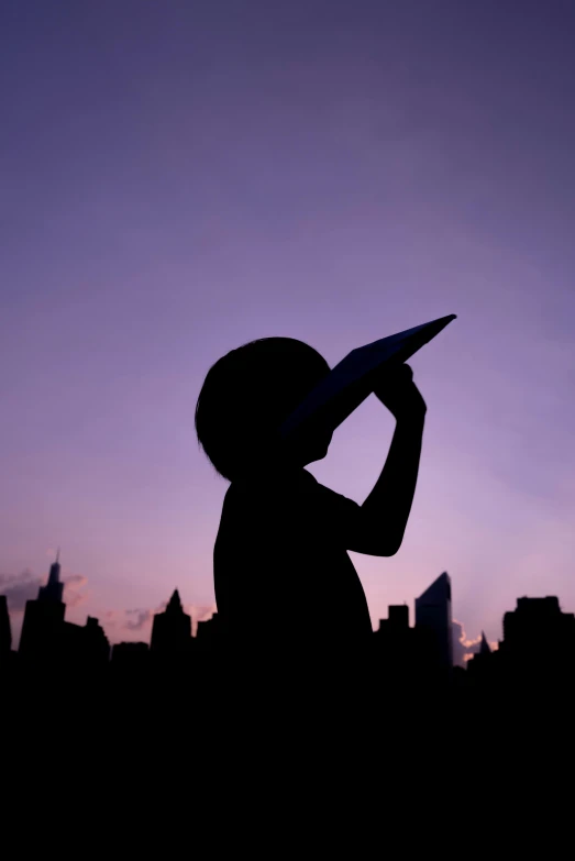 the silhouette of a person with a hat and holding a piece of paper