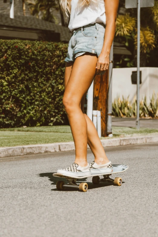 a girl is standing on her skateboard with ripped shorts on