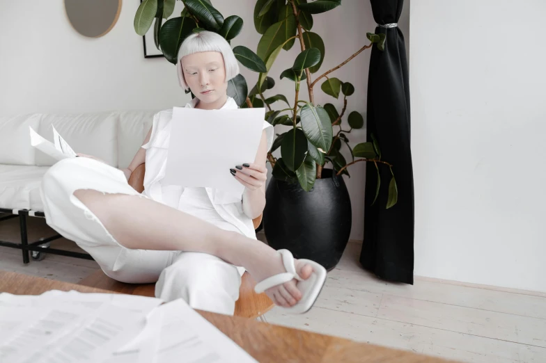 an older woman sitting on a white couch next to a plant