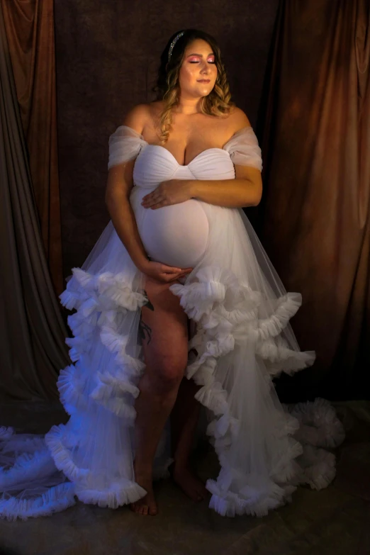 a pregnant woman poses wearing a ruffled dress