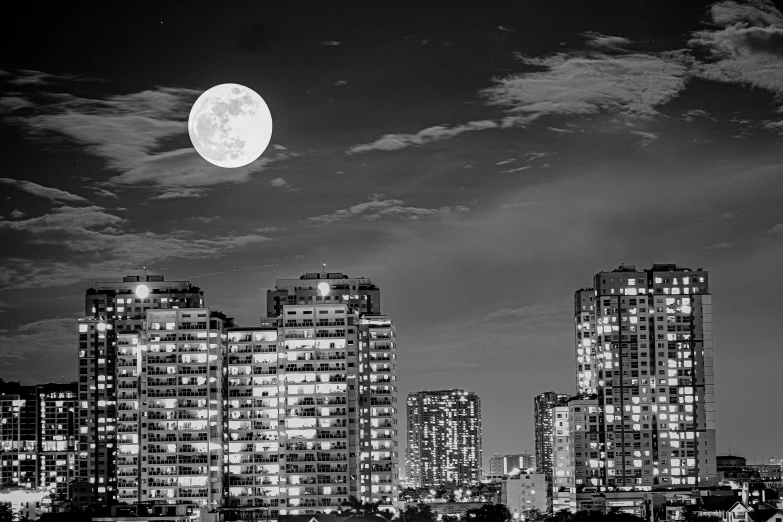 a full moon rises behind buildings in the city