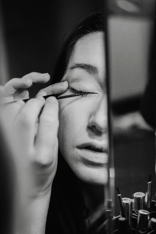 a woman looking in the mirror while doing makeup