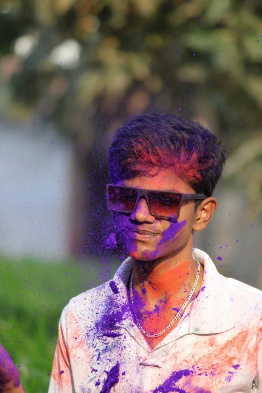 a man in sunglasses with purple paint on his body