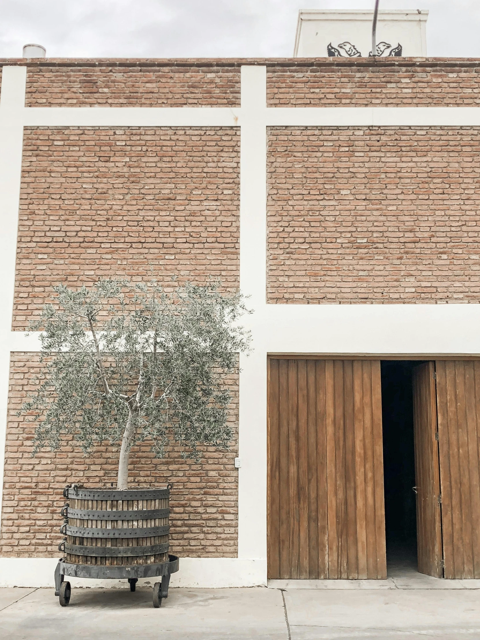 a tree in front of a brick wall and an open entrance