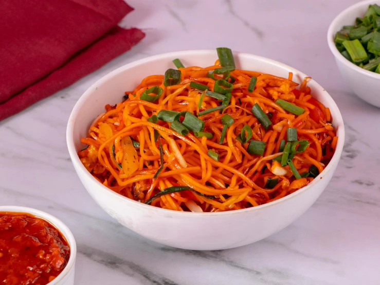 a bowl of shredded carrots with a side of green beans