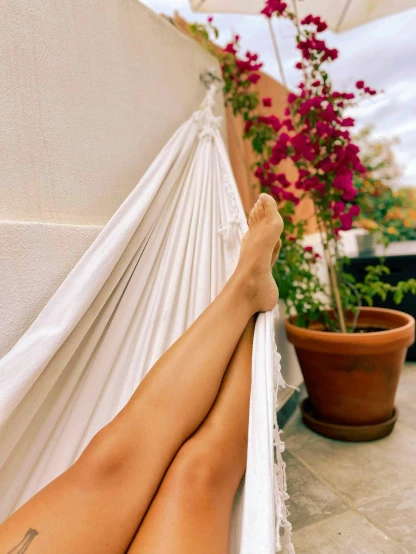 a woman sitting on a hammock with her legs resting in the hammock