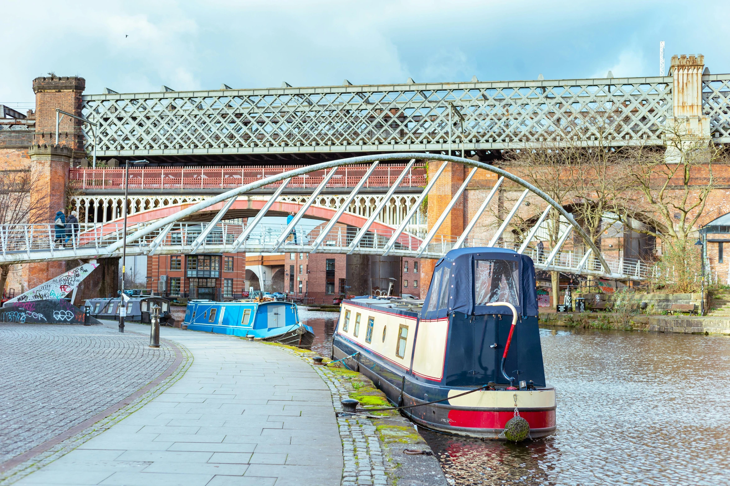 boats sit near the river under the bridge