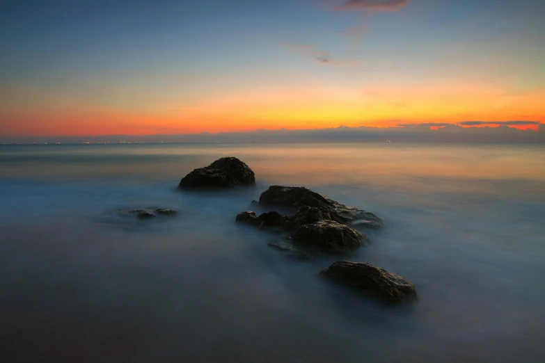 a sunset behind two rocks in the water