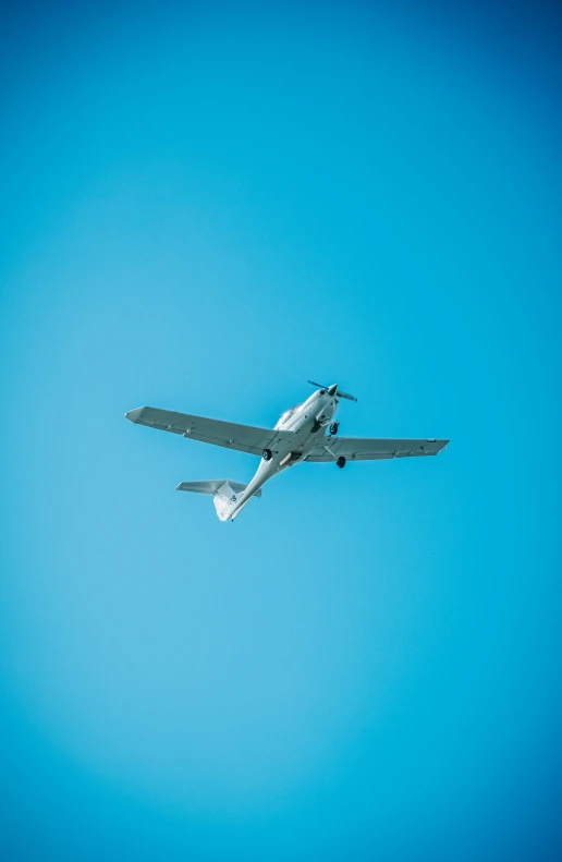 a silver airplane is flying against the clear blue sky