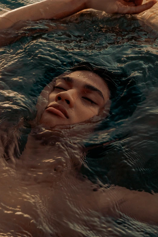 a man laying in water holding onto a tennis ball