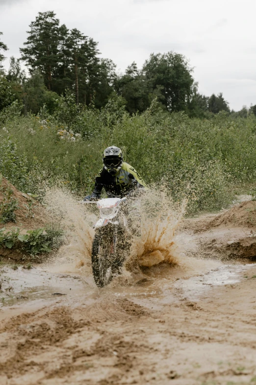 a person is riding on a white dirt bike through mud