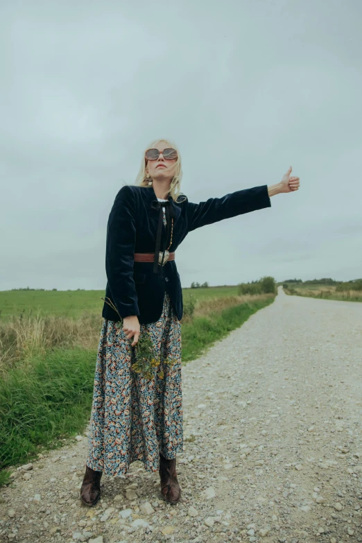 a woman wearing sun glasses standing on a dirt road