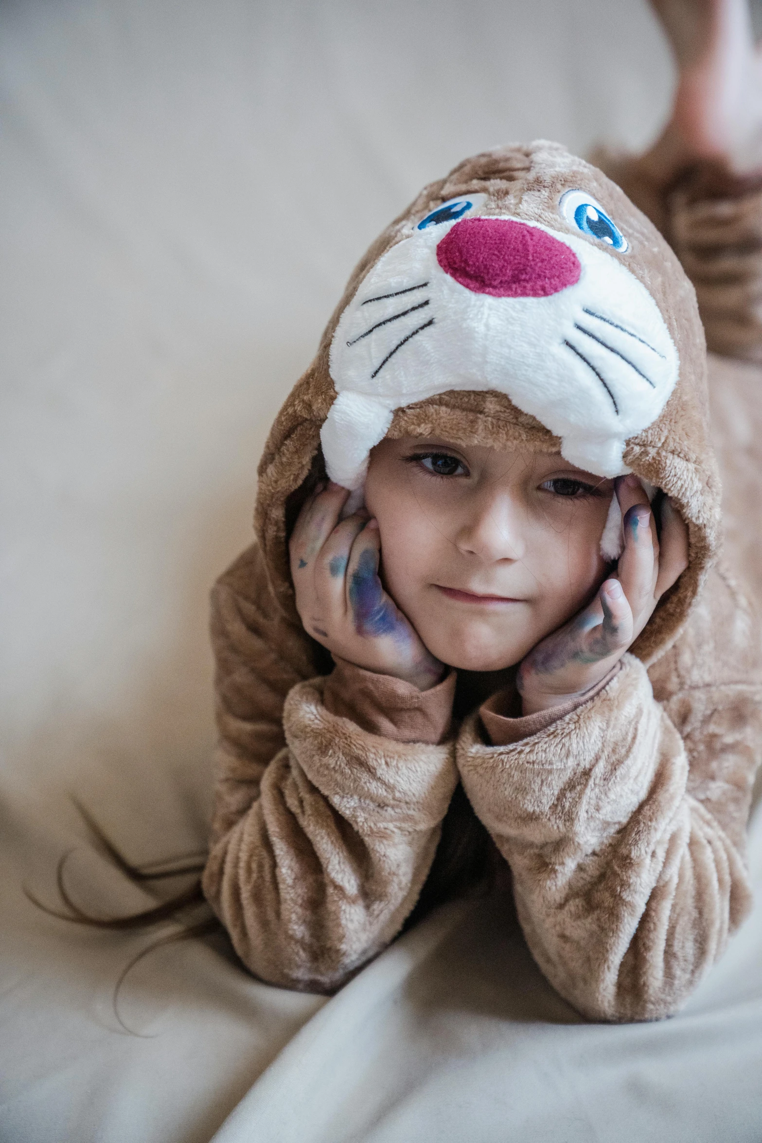 a child laying on top of a white bed covered in a blanket