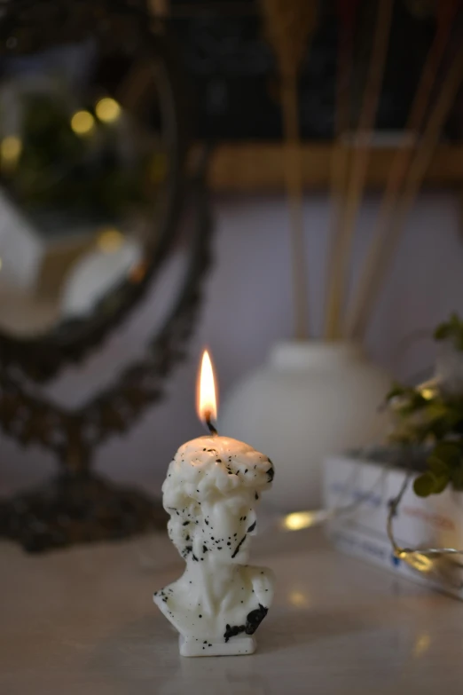 a white candle is placed on a table next to a mirror