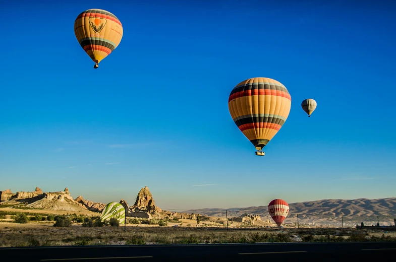 some  air balloons flying in the sky above some hills