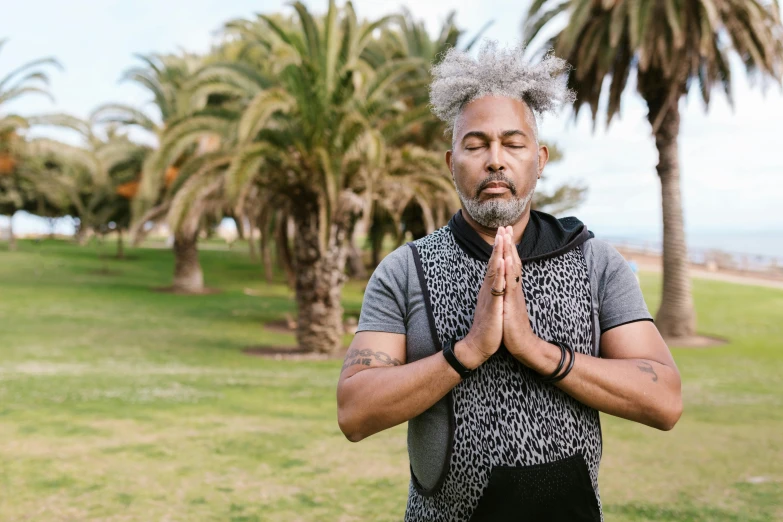 an older man with a grey shirt is standing in a park