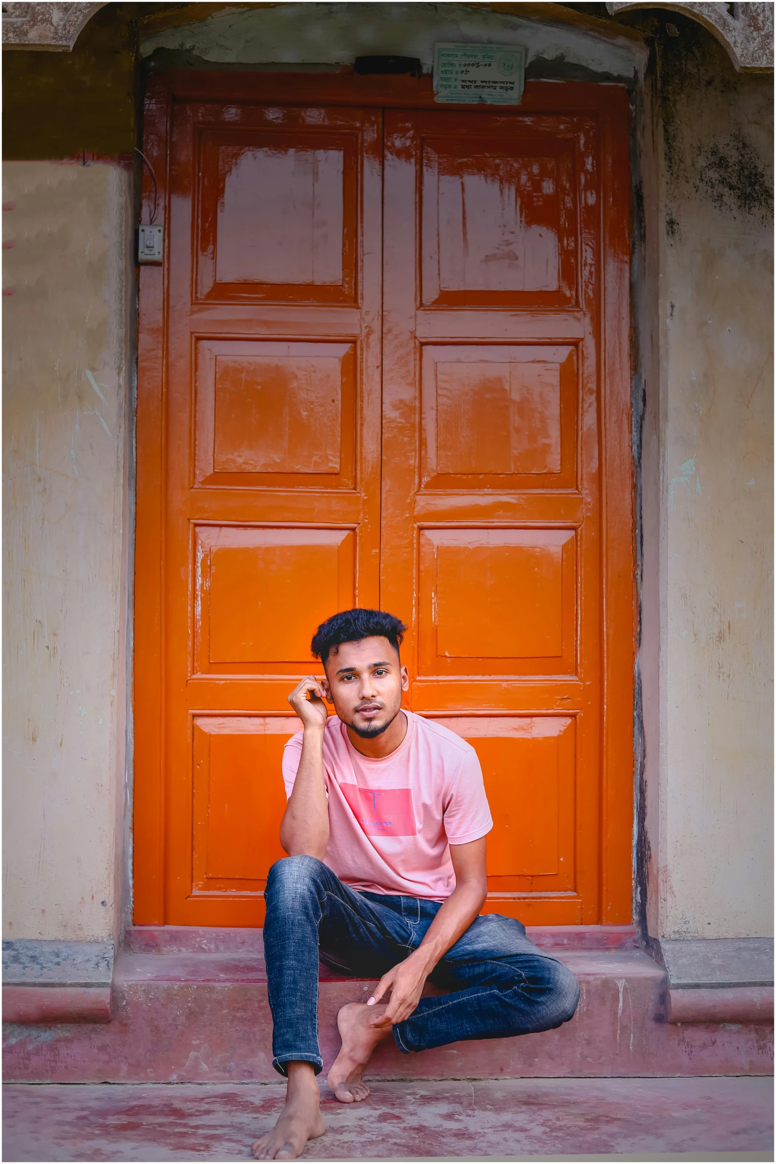 a man sitting on the ground near a red door with a cell phone